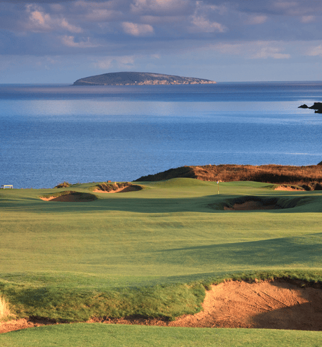 A pristine golf course. Nobody is in the image. Ocean, turf, and sand make for a dramatic and pleasing combination of elements in this rich, saturated image. Sand trap, blue water, rolling hills, and oustanding course conditions also add to the scene. Nobody is in the image, taken with large format camera.