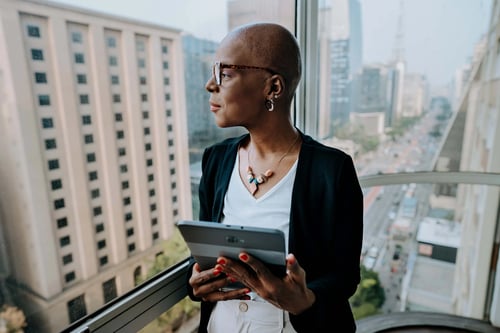 Black senior woman executive overlooking office window downtown