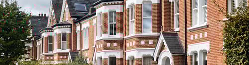 Knight Frank Wandsworth Estate Agents- row of Victorian terraced houses in Wandsworth, West London, characterized by red brick facades, white-framed bay windows, and slate roofs.