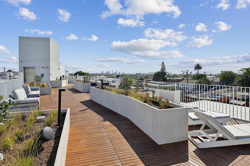 A rooftop patio with white furniture and a wooden deck.at The Wilson, Santa Monica, CA 90405