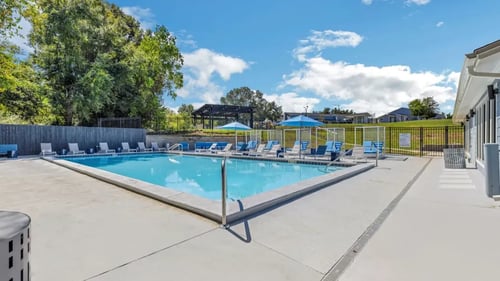 A resort style swimming pool with blue chairs around it at The Lorient Apartments, Pensacola, FL