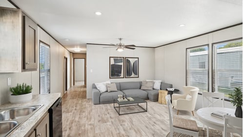 A modern kitchen and living room with a grey sofa and a dining table at Converse Meadows MHC in Converse, TX