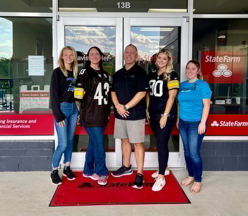 Agent Travis and four team members standing and smiling outside of agency