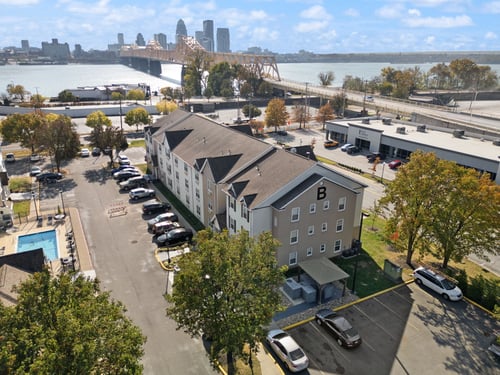 an aerial view of a building with a river and a city in the background at AVIA North Shore in Jeffersonville, IN