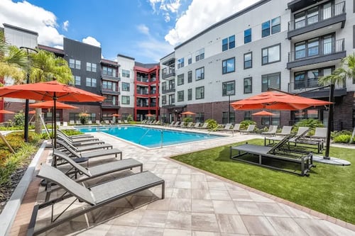 A pool area with sun loungers and a palm tree at Parkway Crossing in Kissimmee, FL