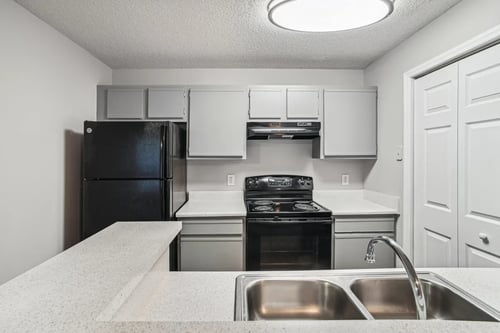 Apartment kitchen with black appliances and white cabinets at Wellington Farms, Charlotte, North Carolina