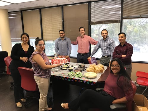 Team members standing and smiling together in office