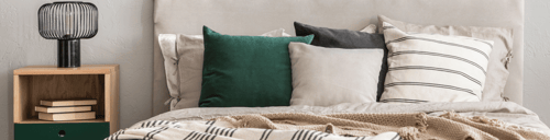7850 East Jefferson - Modern bedroom with cozy bed, decorative pillows, and nightstand lamp