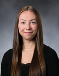 Alyvia Dobs smiles in front of a gray background