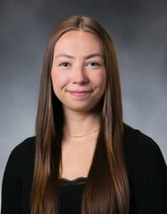 Alyvia Dobs smiles in front of a gray background