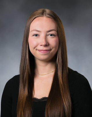 Alyvia Dobs smiles in front of a gray background