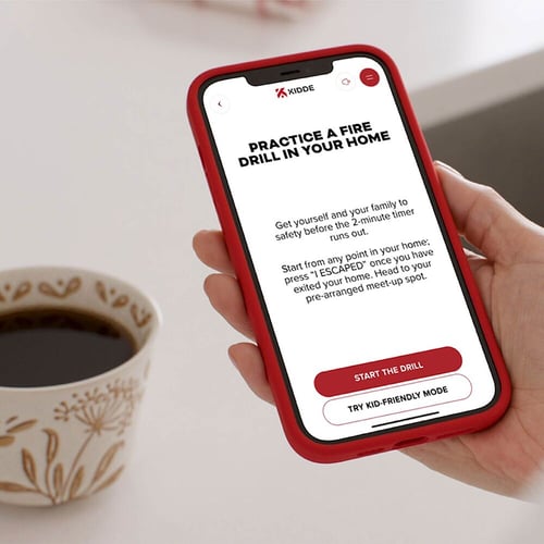 Hand holding phone with coffee mug in background