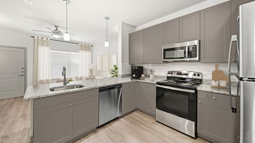 First-floor kitchen and living room with wood-style flooring and taupe cabinets at Camden Leander apartments in Leander, Tx