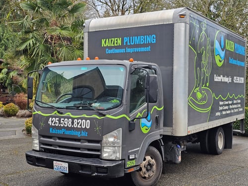 Kaizen Plumbing service truck displaying company branding and contact information, parked outside a residential home.