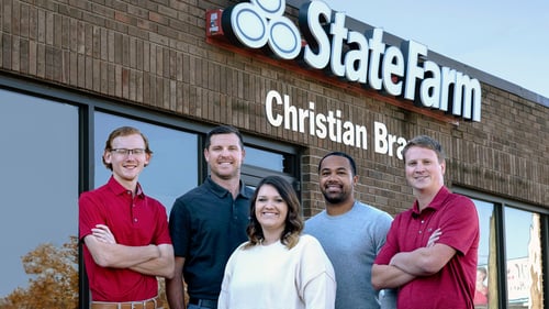 Agent Christian and team members standing and smiling together outside of office