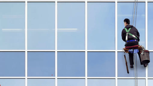worker cleaning a large window