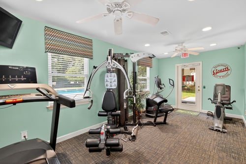 A gym with a treadmill, elliptical machines, and other exercise equipment.