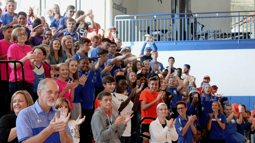 large crowd of students and adults cheering