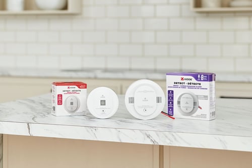 Two new Kidde Detect alarms sit on a counter next to the packages they came in.