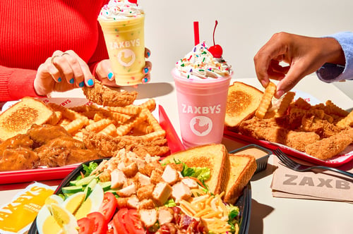Zaxbys chicken meals, salads, fries, toast, and milkshakes on a dining table