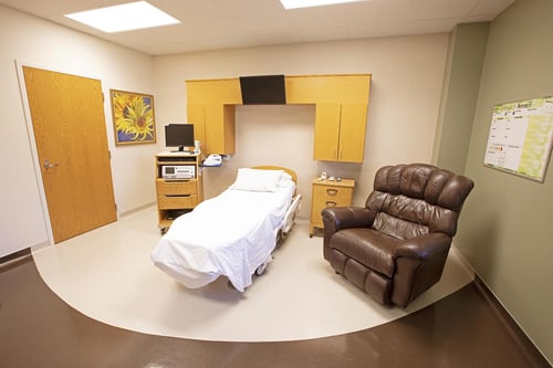A labor and delivery room with a birthing bed and recliner.
