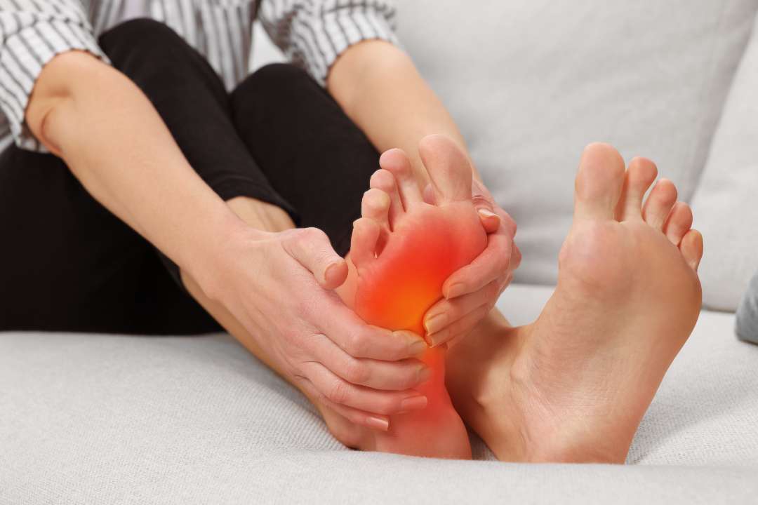 arthritis symptoms woman suffering from foot pain sofa indoors closeup