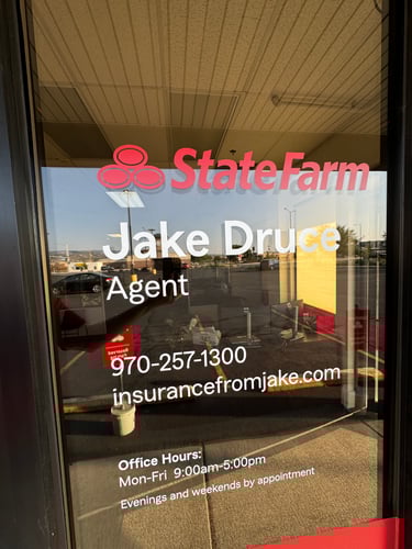 A glass window with the information for Jake Druce State Farm and the hours