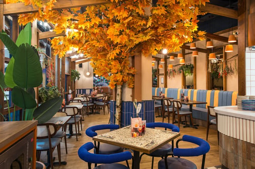 Interior of Zizzi Belfast Odyssey showing wooden tables, blue cushioned seating, copper details, and nautical-themed décor.