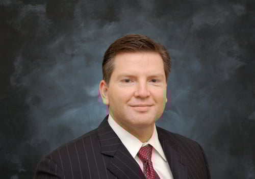 Sergio wearing a suit and red tie smiling