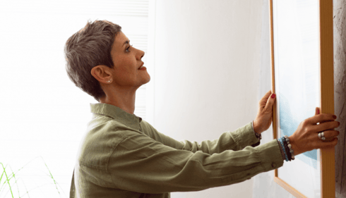 woman hanging art on a wall