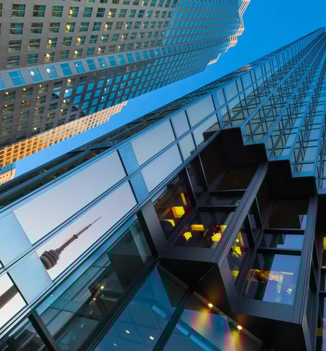 A bottom-up view of an office building in Toronto with the reflection of the CN Tower.
