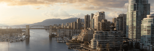 A golden-hour waterfront cityscape featuring a iconic bridge spanning calm waters, with a modern skyline of glass towers rising behind it and mountains visible in the distance. Sailboats dot the marina in the foreground, while warm sunlight bathes the entire scene. The image conveys stability, growth, and sophisticated aspiration, perfect for a wealth management brand.