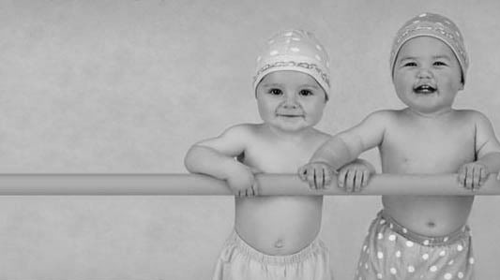 2 babies standing in a crib