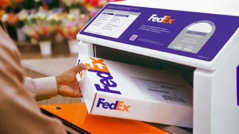 A person putting a package into a FedEx Drop Box