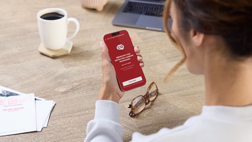 A woman is looking at her smart phone, showing a CO alert.
