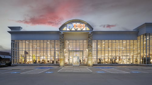 Rooms To Go Kids store facade in Rockwall, TX, at dusk, with large glass windows and prominent signage.