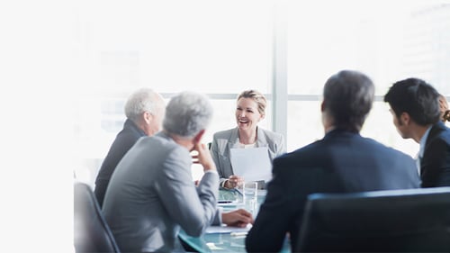 individuals in a board room having a discussion and laughing