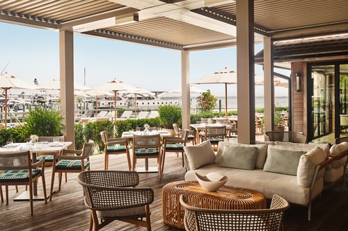 Outdoor dining terrace at Alba Spiaggia, Montauk Yacht Club, with marina and boat views.