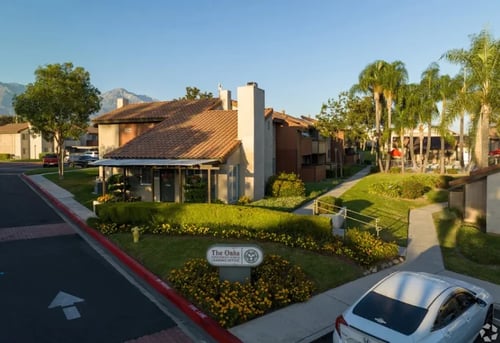 Aerial view of The Oaks apartment community with landscaped gardens and residential buildings at The Oaks Apartments in Upland, CA