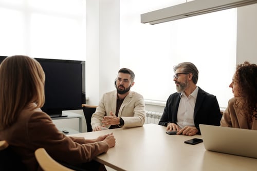 Business owner meeting with his employees around table.