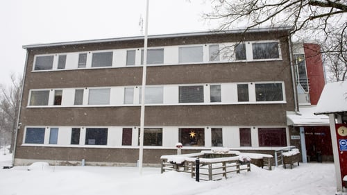 Ulkokuva Malmikodista. Rakennus on kolmikerroksinen ja ja julkisivu on tummaa kiveä. Maassa on kaunis kerros valkoista lunta.