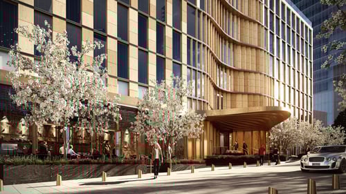 Modern hotel exterior with curved wooden façade and blossoming trees along the sidewalk