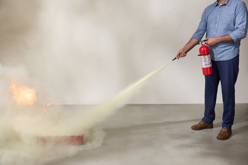 A man puts out a fire with a fire extinguisher.