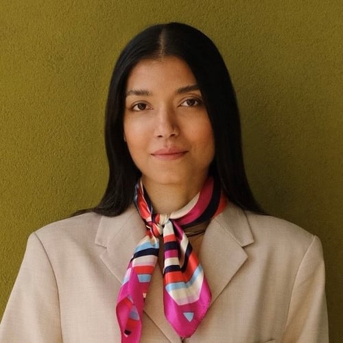 Headshot image of woman in beige blazer and multicoloured scarf