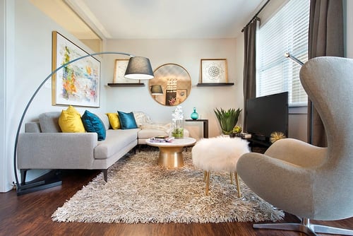 A living room with a grey couch, a white chair, and a coffee table at The Olivia Apartments, Carmel, IN