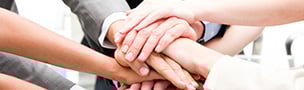 A group of diverse hands placed together in a stack, symbolizing teamwork and unity. The background is light, enhancing the collaborative vibe.