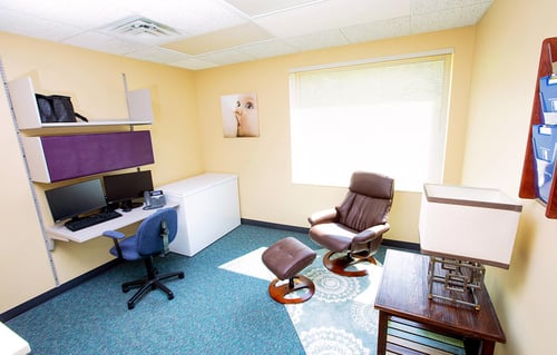 A nursing support room showing computer, computer chair and rocking recliner with footrest.