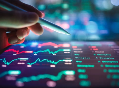 Tablet filled with various stock market graphs with hand holding tablet pencil