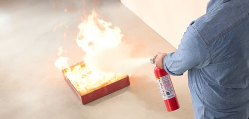 Man using a Kidde fire extinguisher.