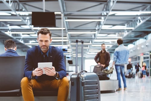 Man sitting in airport looking at tablet